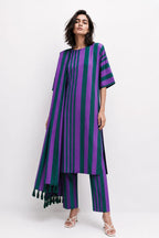 A model wearing a purple and dark green vertically striped tunic top with matching striped pants and dark green tassels, photographed against a plain white studio background.
