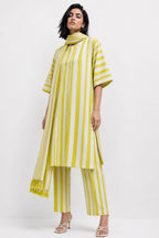 A model wearing a yellow and white vertically striped tunic top with matching striped pants and white heeled sandals, photographed against a plain white studio background.